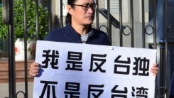 An Huang holds a sign where he decries Taiwan's independence from mainland China. 